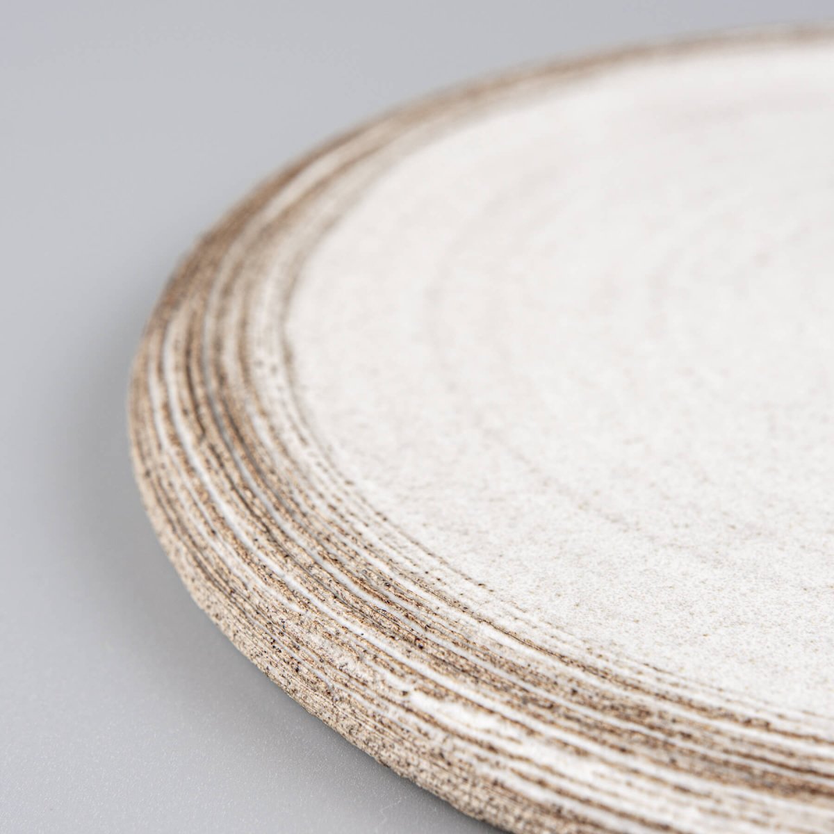 Detail of textured rim on artisan-made ceramic plate in matte white.