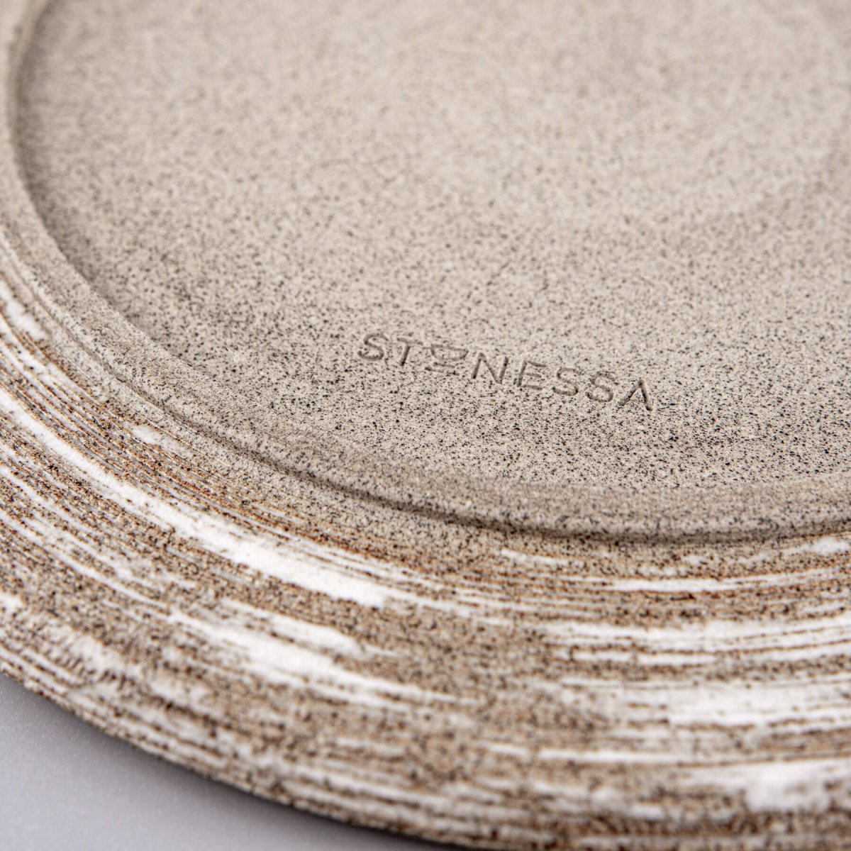Close-up of detailed carved rim and matte finish on artisanal ceramic plate.