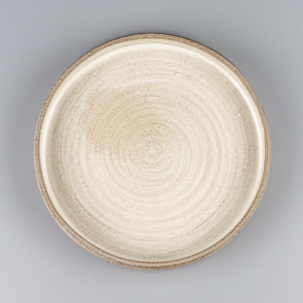 Elegant stoneware dinner plate with matte white glaze and hand-carved textured edges.