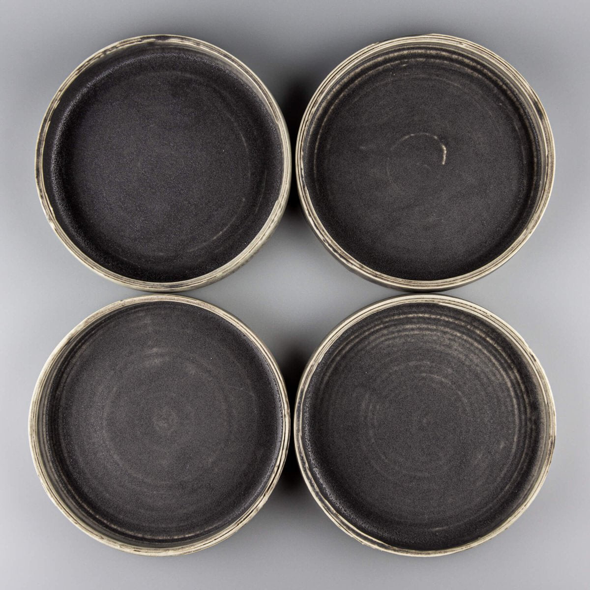 Overhead view of four handmade ceramic plates arranged for fine dining presentation.