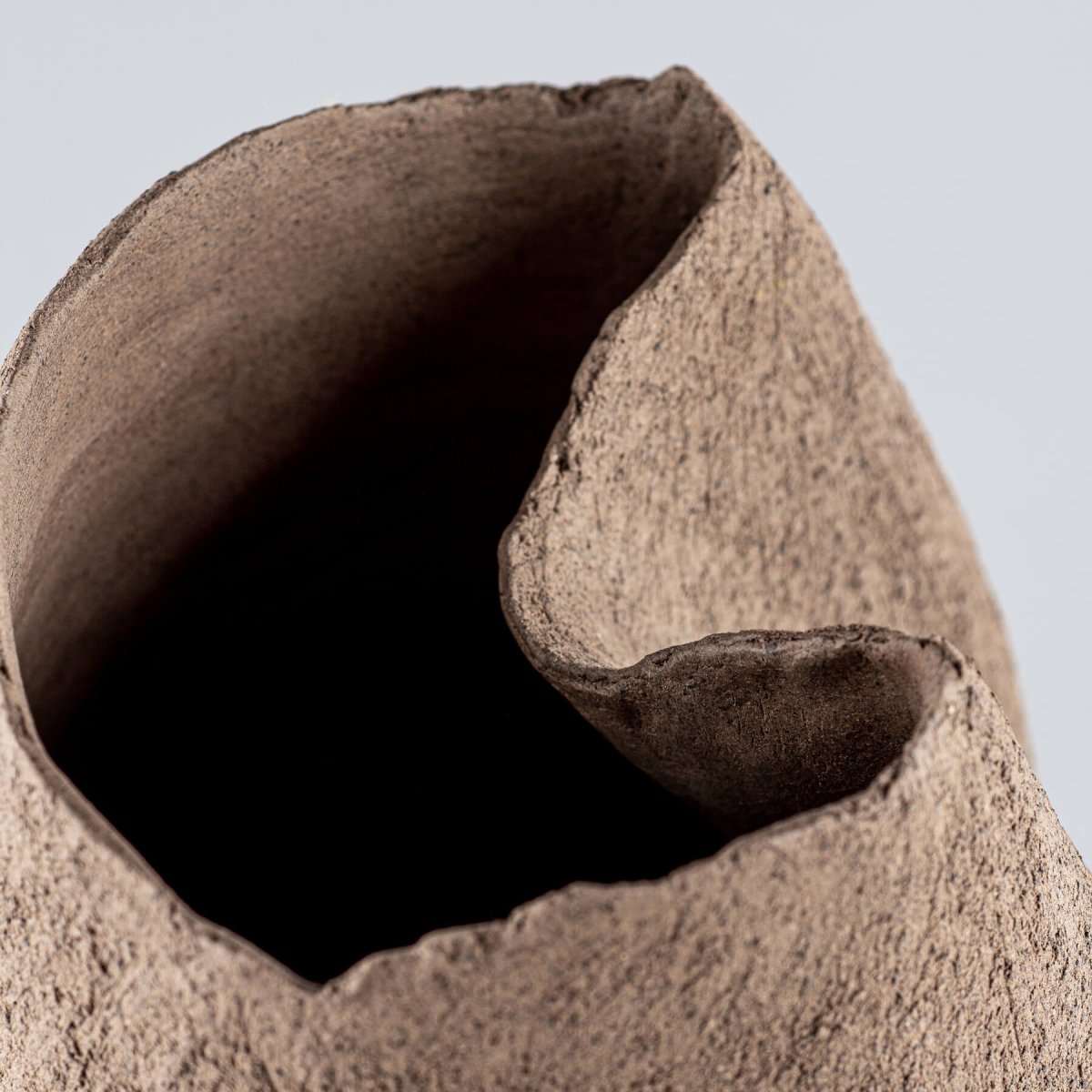 Decorative brown stoneware vase featuring a textured, unglazed surface for interior design.