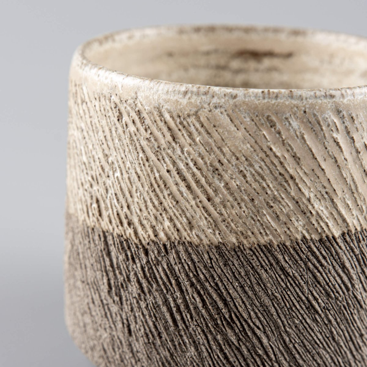 Handcrafted pottery coffee mug with carved stoneware texture and half-glazed matte finish for modern tableware.
