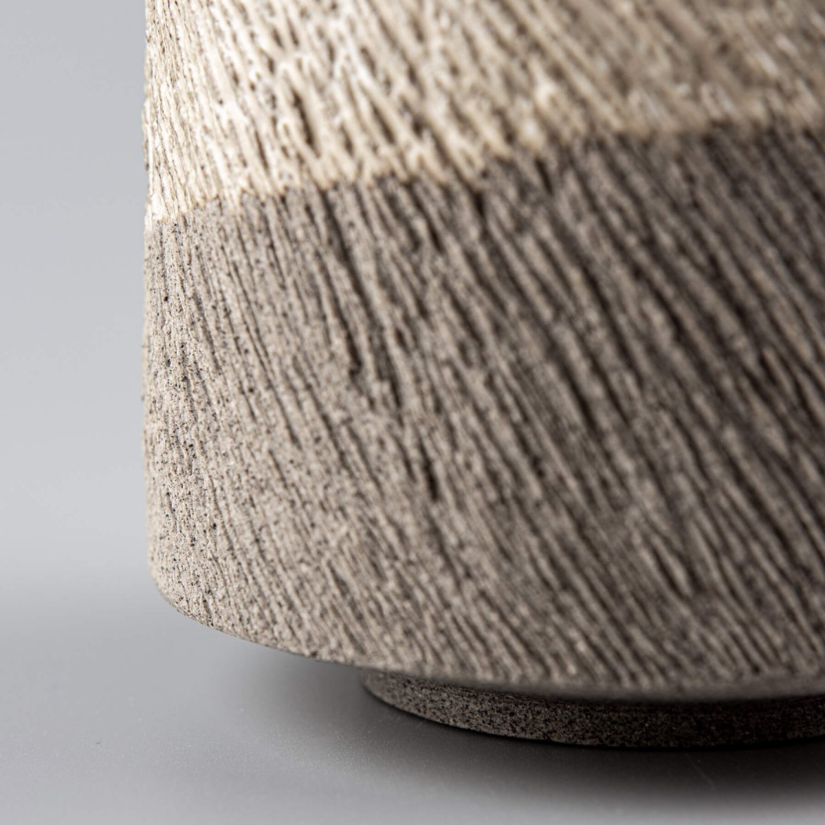 Side view of pottery coffee mug showing textured carved lines and contrasting glaze.