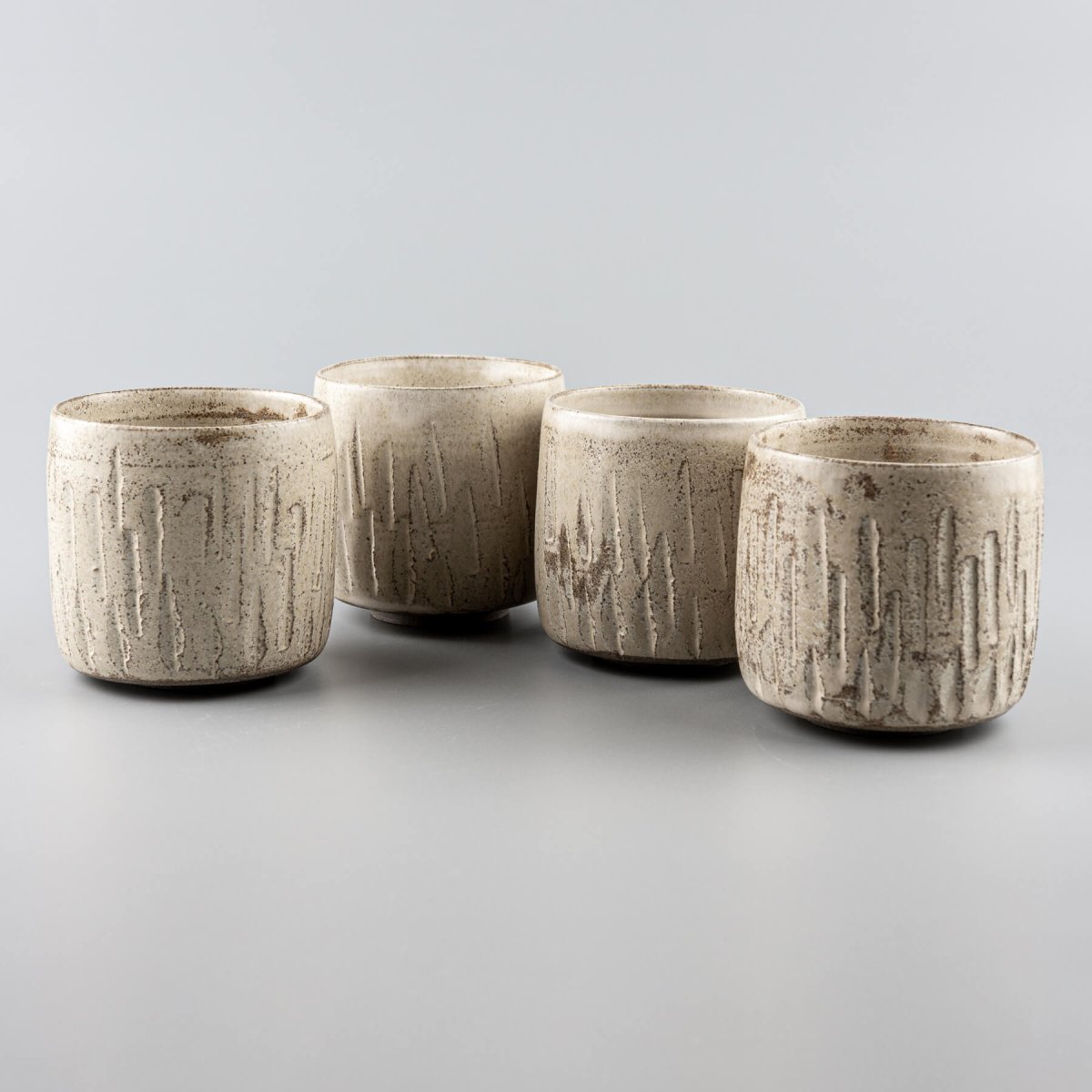 Ceramic handmade cups set with carved stoneware texture and matte glaze finish.