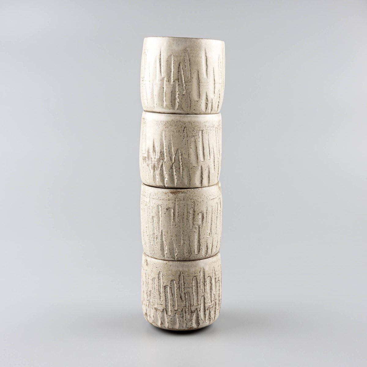 Stacked ceramic handmade cups with carved stoneware design and matte glaze.