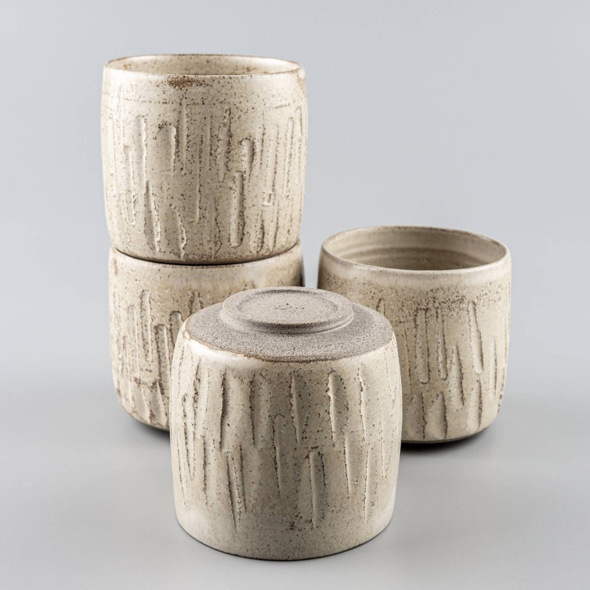 Stacked ceramic handmade cups with carved stoneware design and natural glaze.