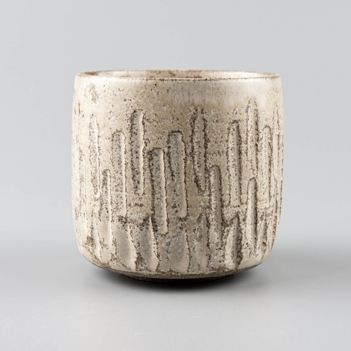 Detailed carving patterns on ceramic handmade cup with matte glaze.
