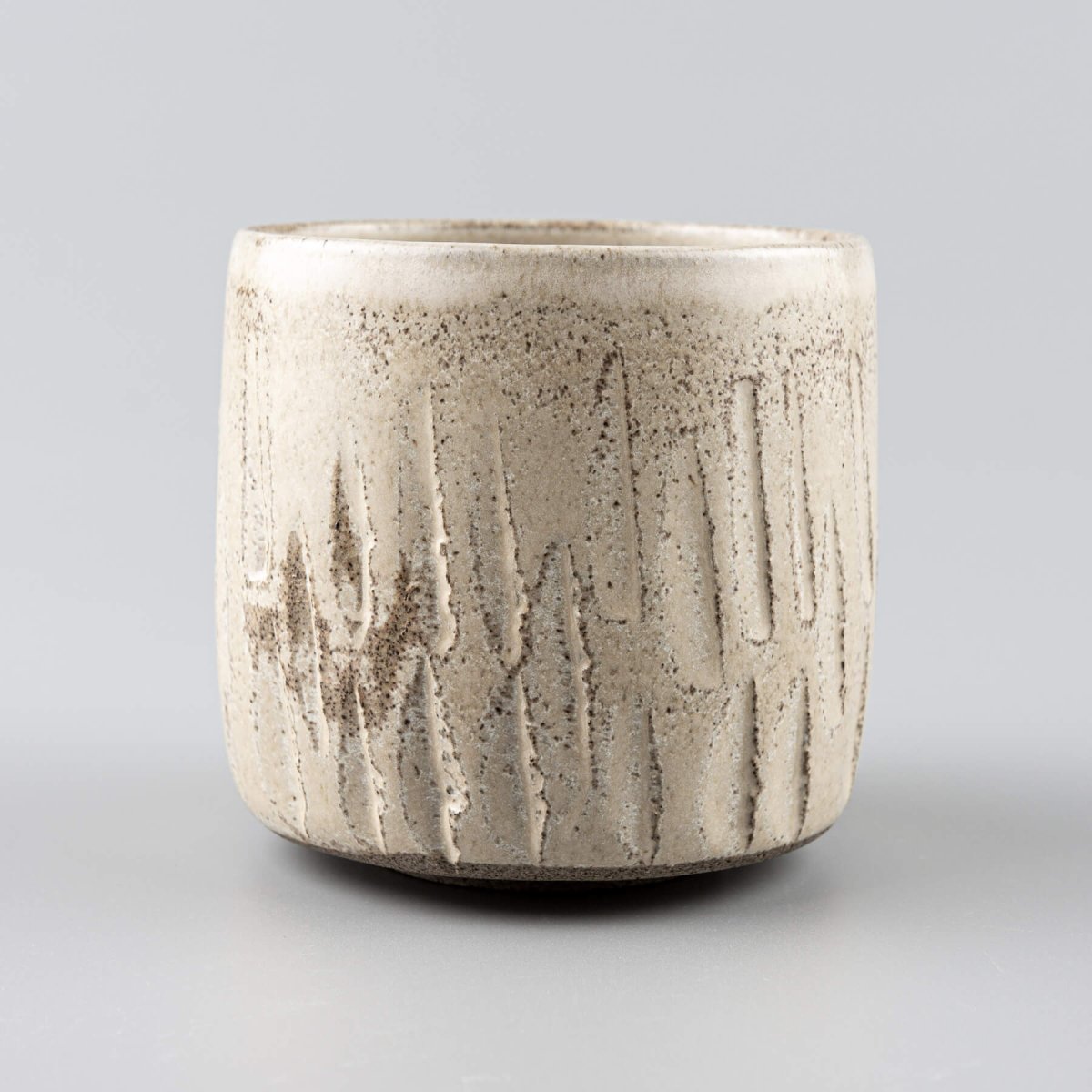 Artisan-crafted ceramic handmade cup with rustic carved stoneware texture.