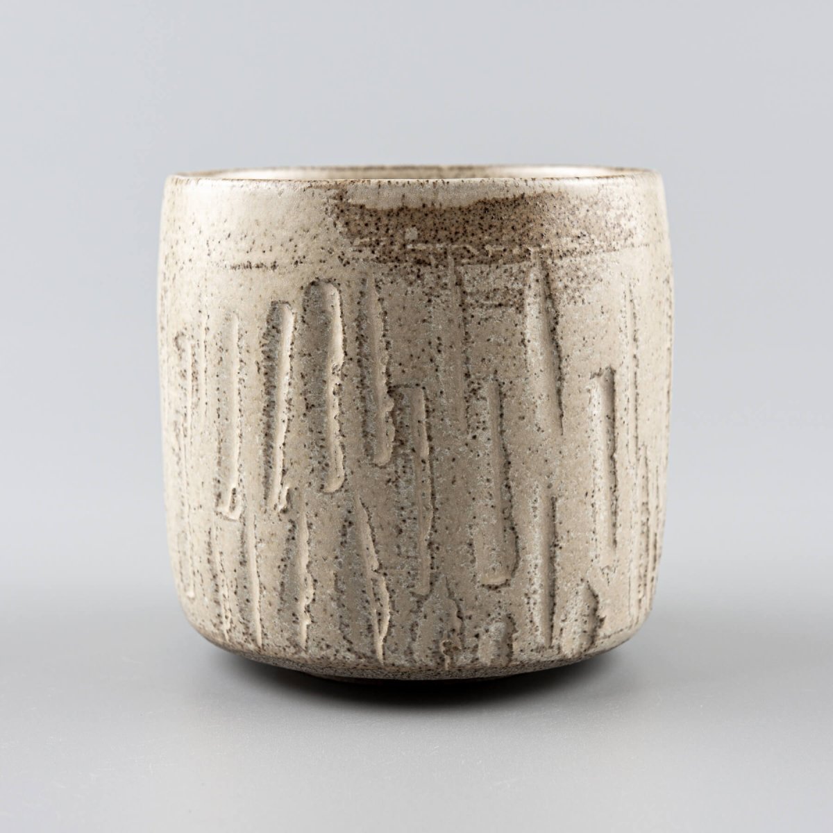 Single ceramic handmade cup with textured carvings and rustic matte finish.