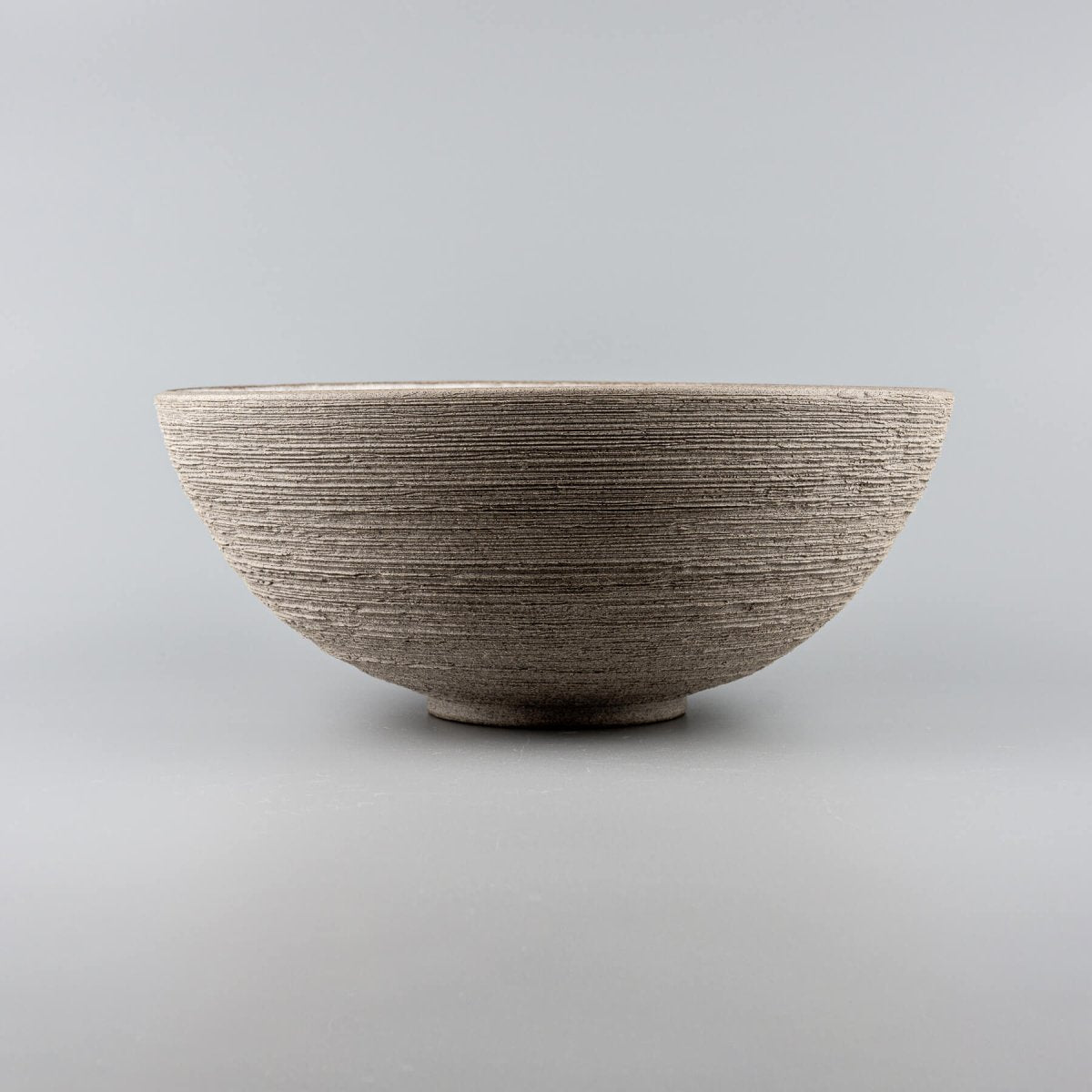 Handcrafted ceramic serving bowl with textured outer surface and matte glazed interior for fine dining and home use.