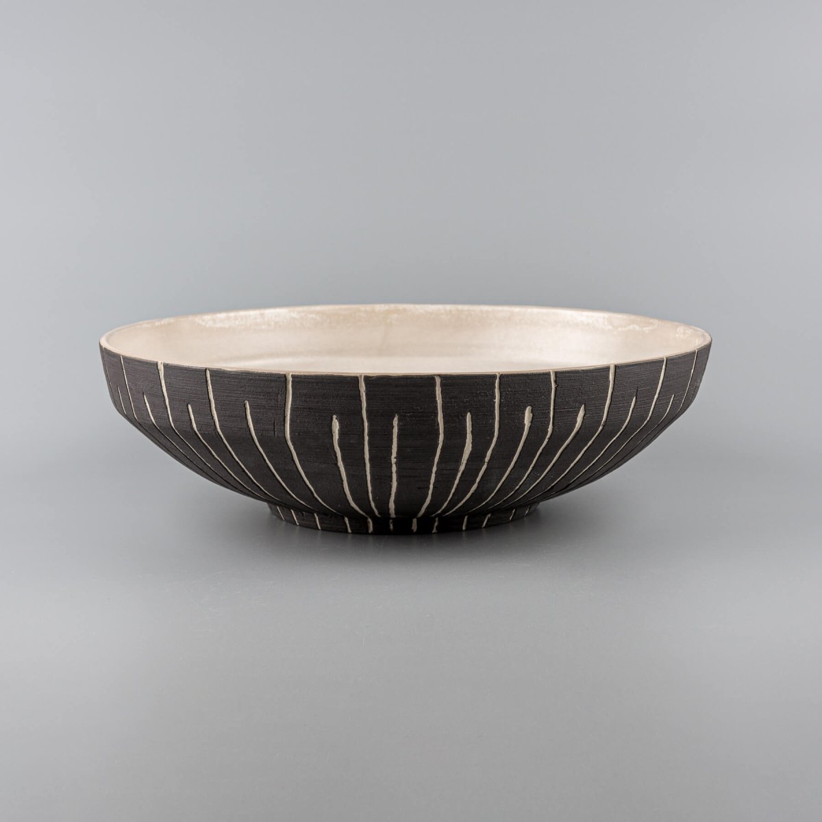 Large handmade decorative bowl with carved vertical slip lines and matte glazed interior for home and restaurant use.