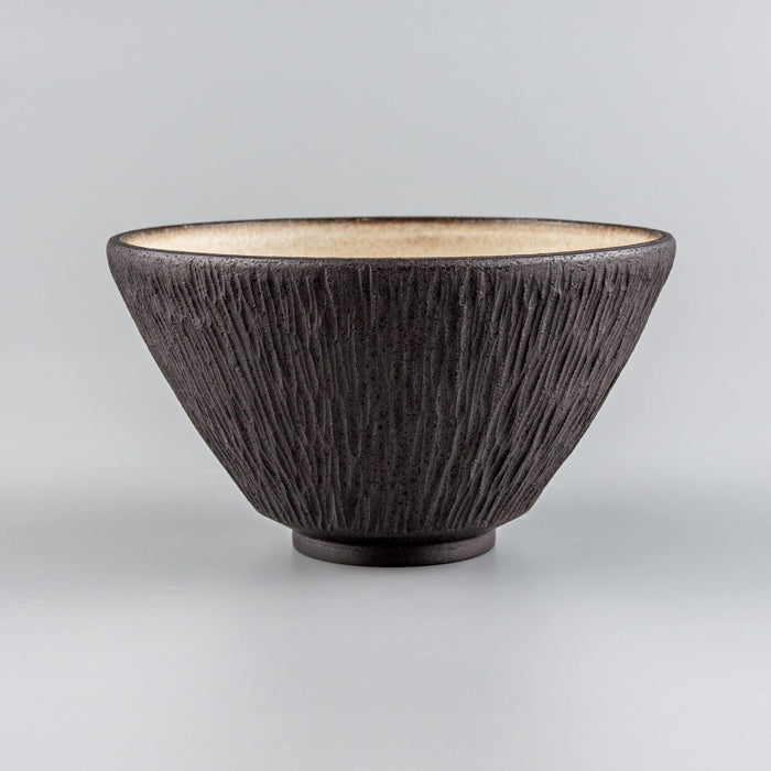 Handmade stoneware bowl with carved black exterior and beige glazed interior, ideal for luxury dining.