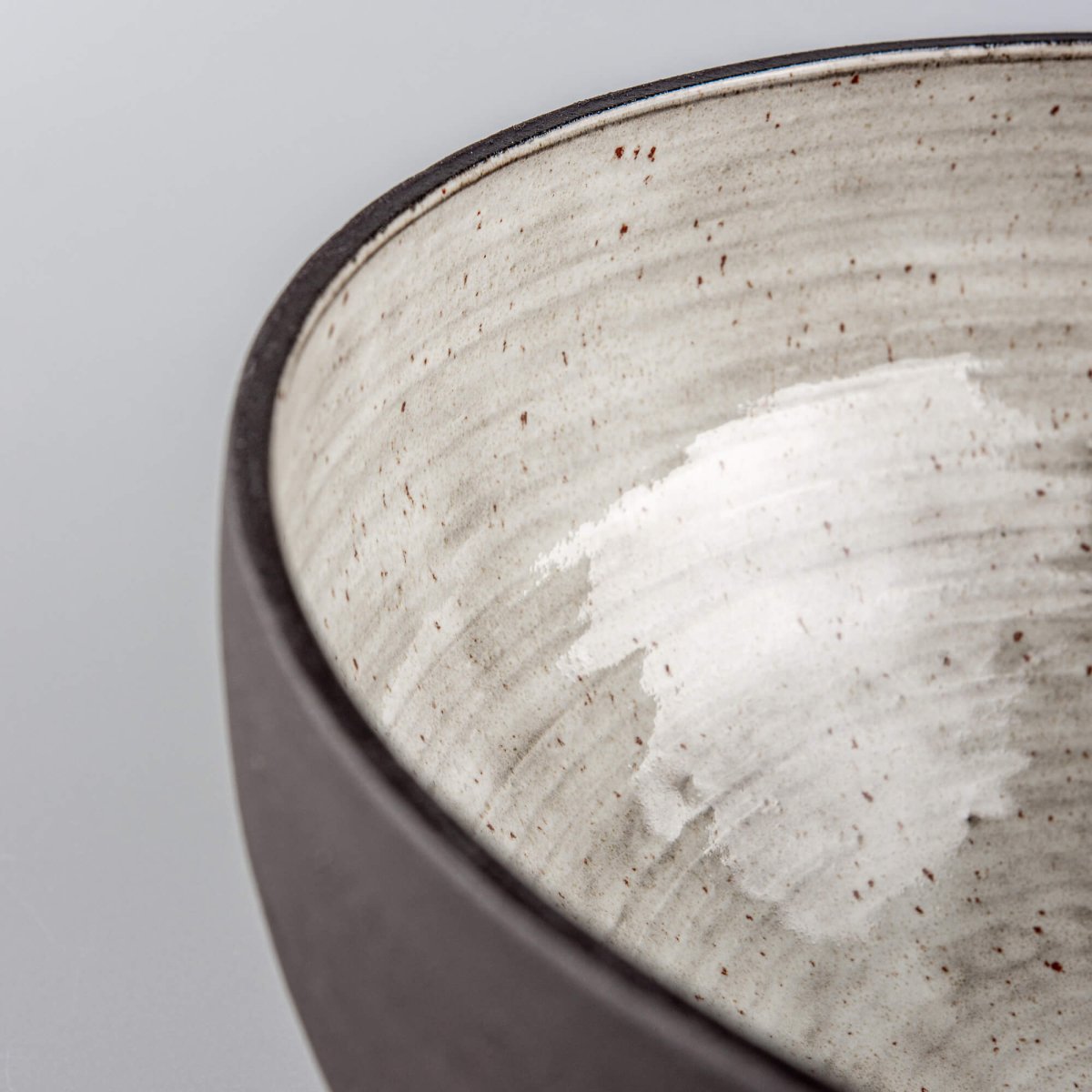 Bottom view of handmade serving bowl with dark textured ceramic exterior and stable footed base.