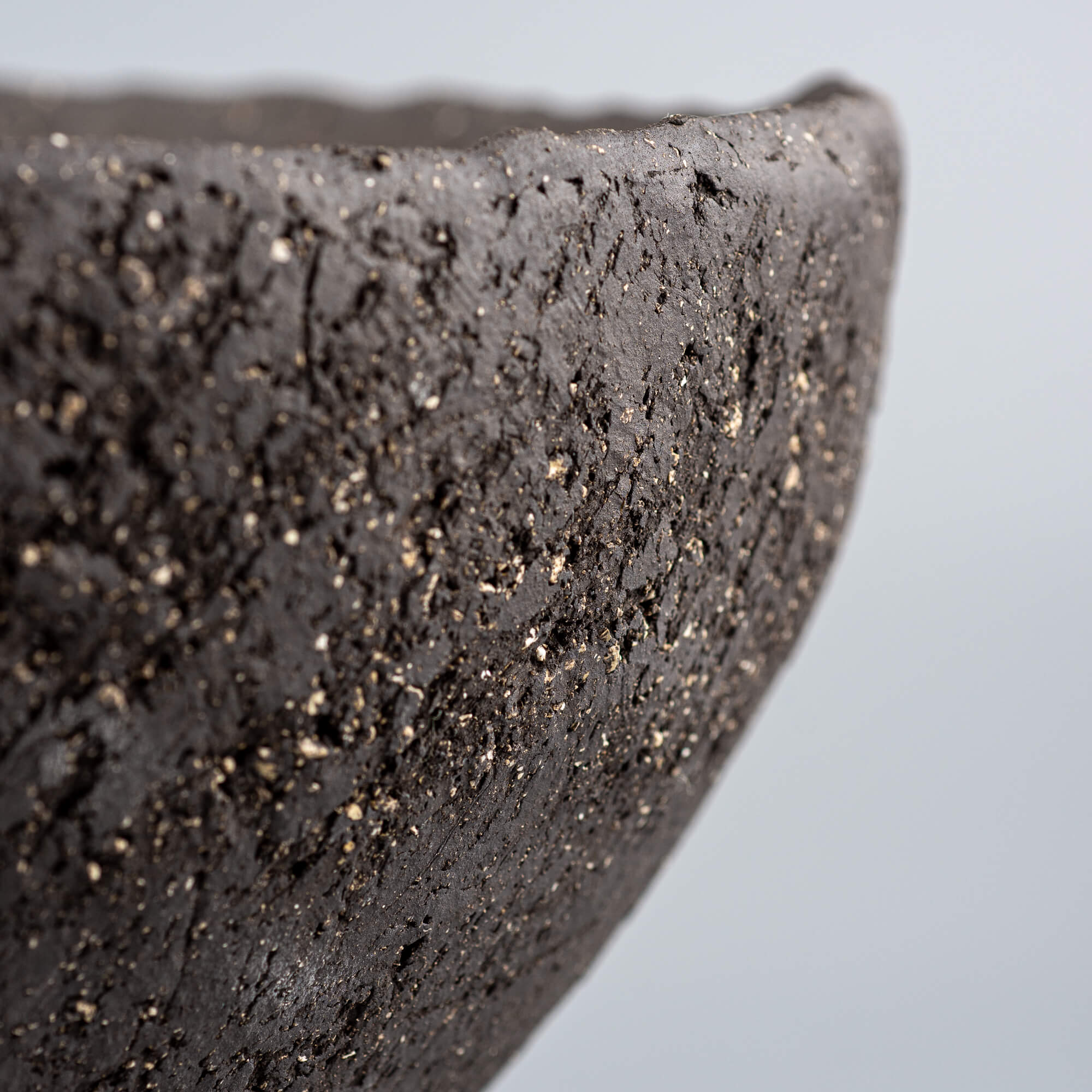 Handcrafted centerpiece edge close-up with dark textured ceramic finish for luxury homes and fine dining spaces.