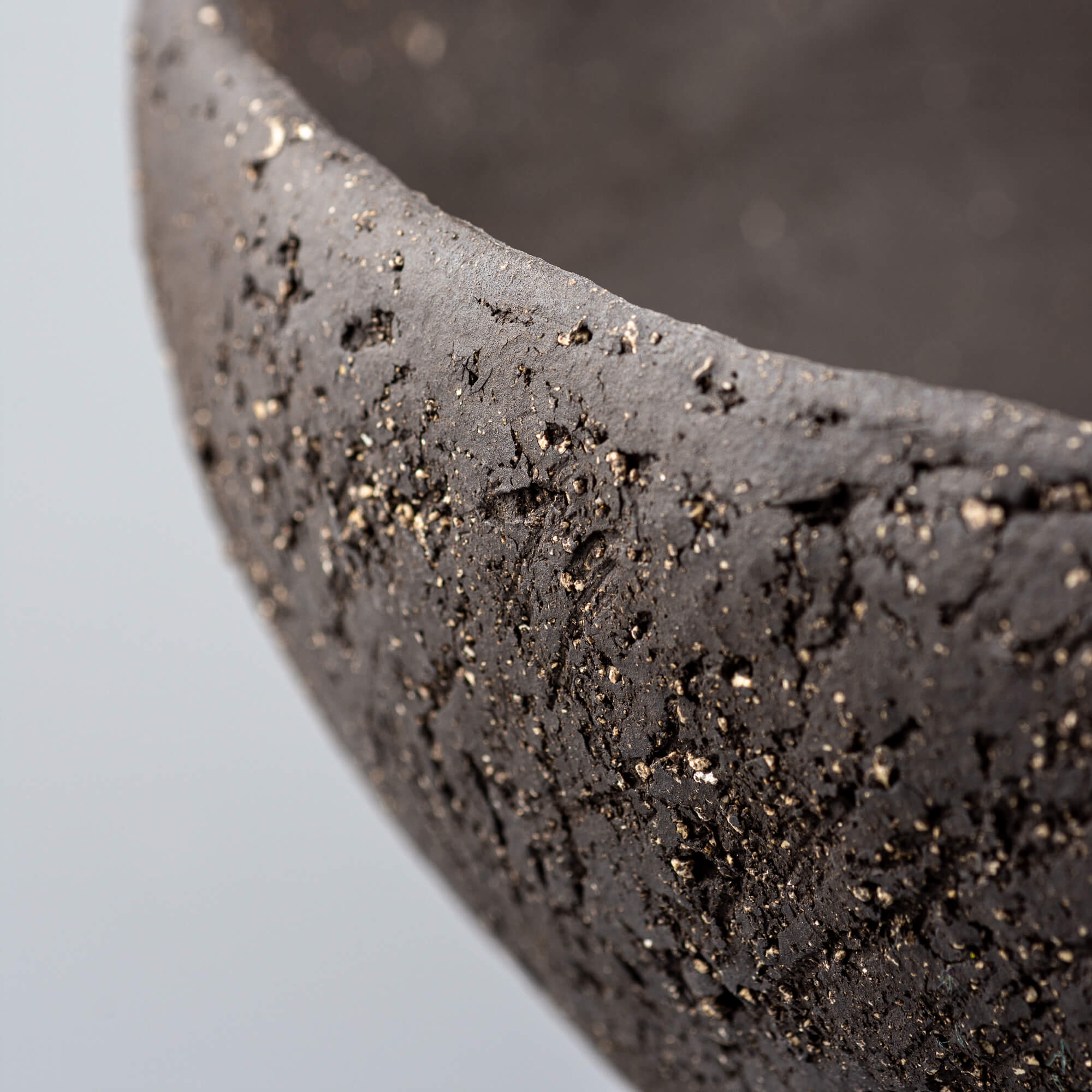 Handcrafted centerpiece rim detail with dark stoneware texture for boutique hotel and restaurant interiors.