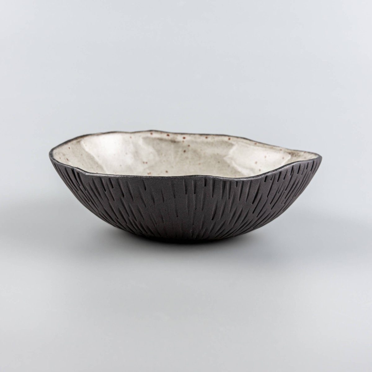 Handmade ceramic bowl with textured exterior and speckled glaze, designed for fine dining and luxury restaurant tableware.