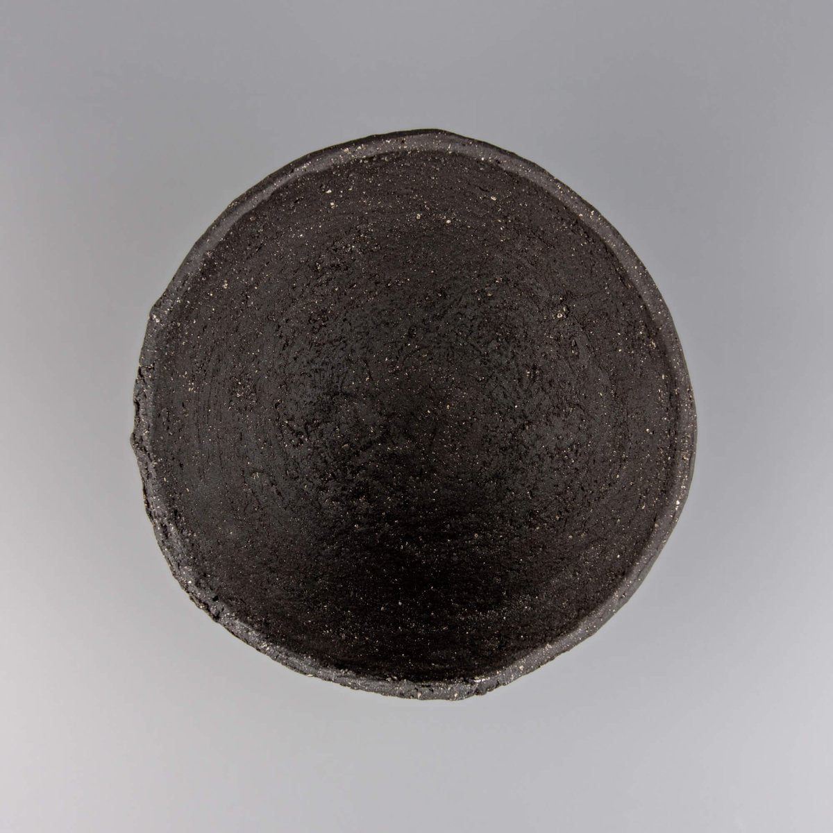 Handmade decorative bowl in dark stoneware with organic rim, ideal for interior design and collectible pottery styling.