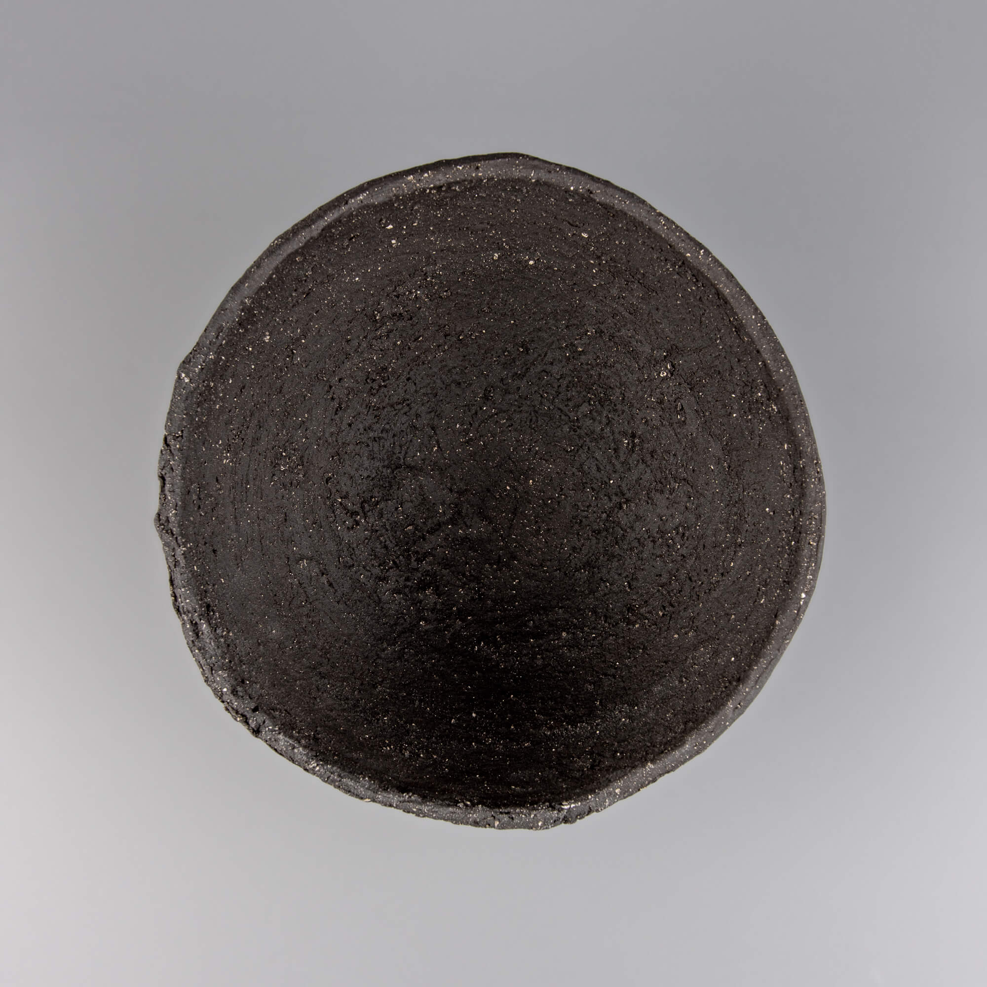 Handmade decorative bowl in dark stoneware with organic rim, ideal for interior design and collectible pottery styling.
