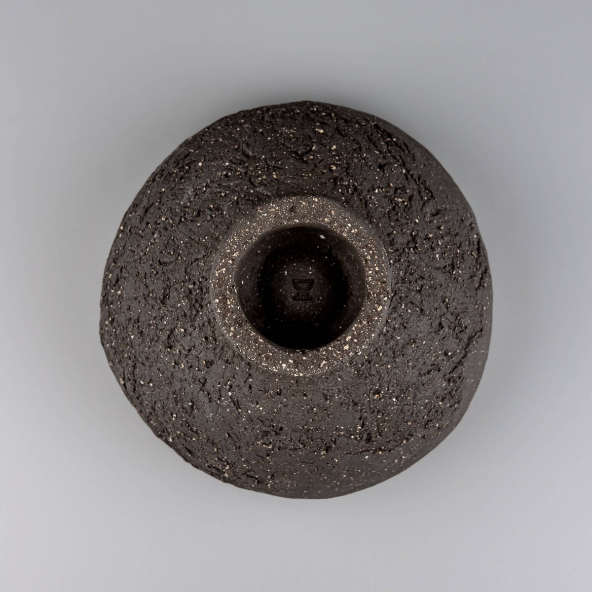 Bottom view of handmade decorative bowl showing raised foot, dark speckled clay, and sculptural handmade construction.