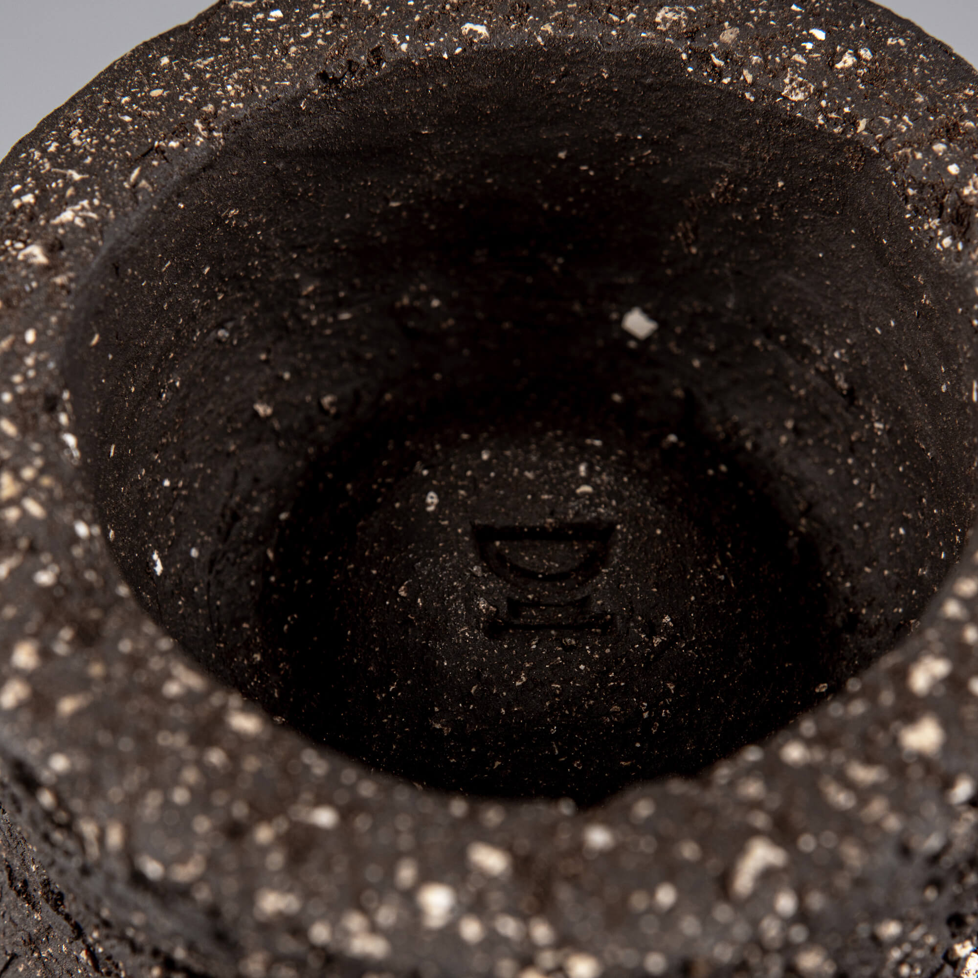 Interior detail of handmade decorative bowl with deep foot ring, raw dark ceramic texture, and artisan pottery finish.