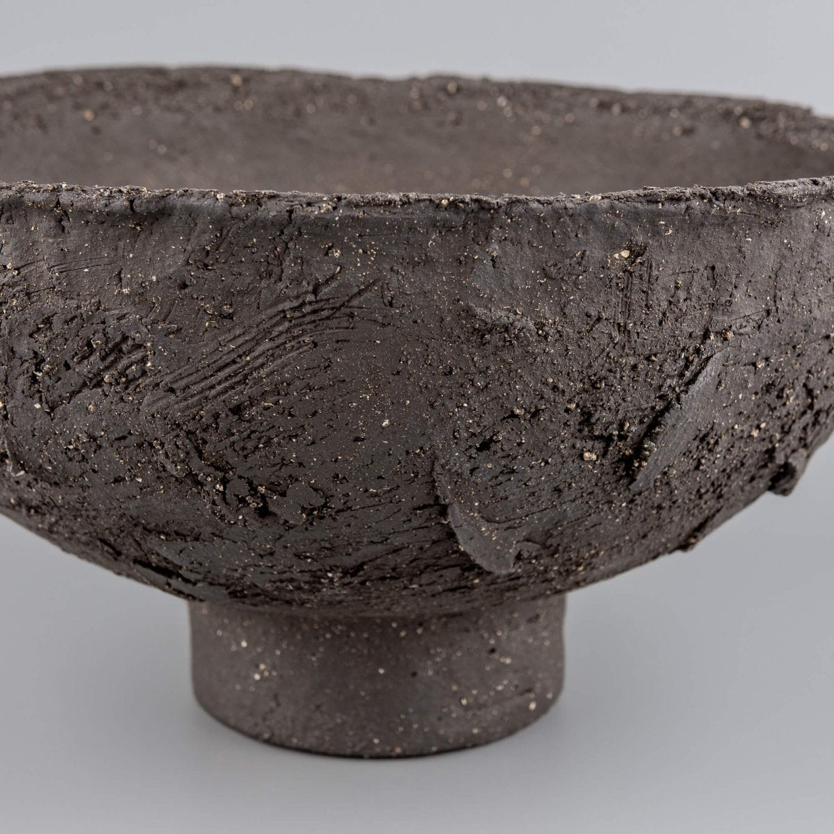 Handmade decorative bowl side detail with raw charcoal clay, raised texture, and sculptural centerpiece presence.