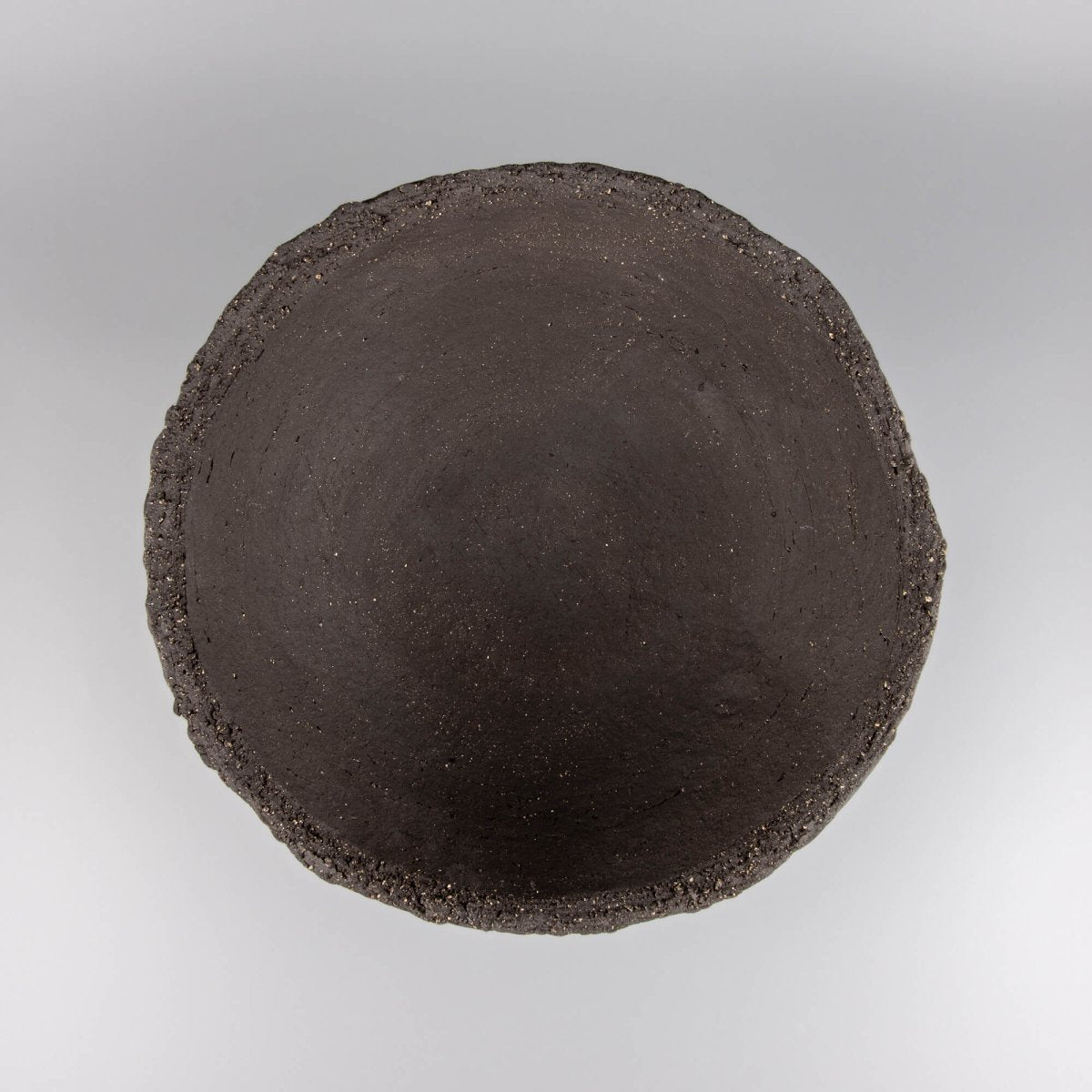 Handmade decorative bowl seen from above with dark matte interior, organic rim, and collectible pottery character.